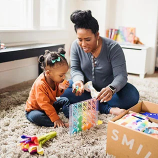 Child and mother playing with the Drop & Match Dot Catcher from The Helper Play Kit