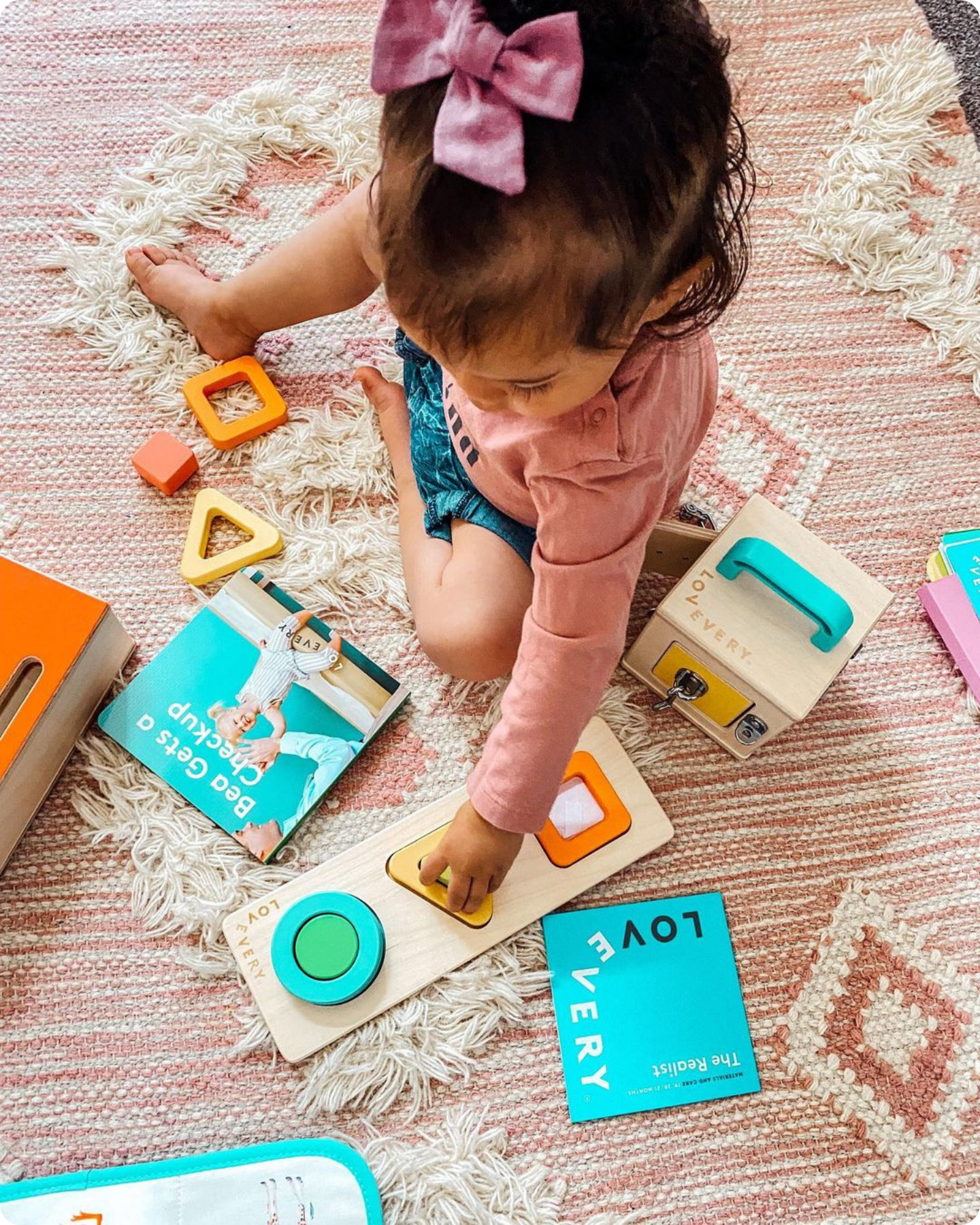 Child playing with several playthings from The Realist Play Kit